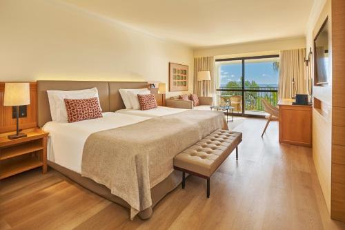 a large bedroom with a large bed and a balcony at Hotel Porto Mare - PortoBay in Funchal