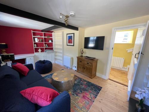a living room with a blue couch and a tv at Central Woodstock Townhouse nr Blenheim Palace in Woodstock