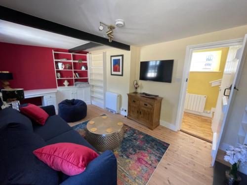 a living room with a blue couch with red pillows at Central Woodstock Townhouse nr Blenheim Palace in Woodstock