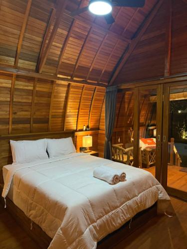 a bedroom with a large bed in a room with wooden walls at Qchen Cuan Cabin Amed in Amed