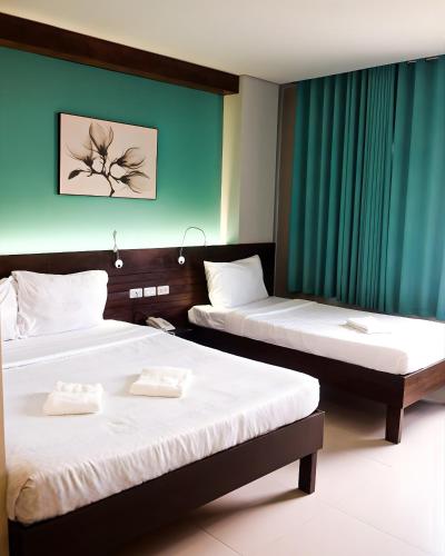 two beds in a hotel room with green curtains at Cresebo Mansion in Tagbilaran City