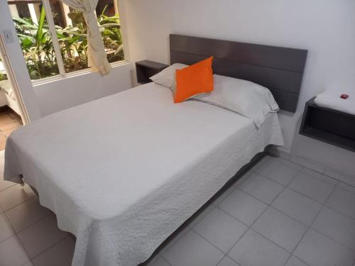 a bedroom with a bed with an orange pillow at Hotel Tame Real in Tame