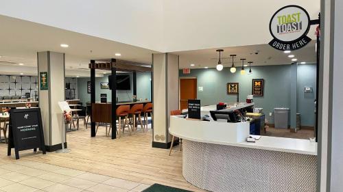 a restaurant with a waiting area with tables and chairs at Holiday Inn Hotel & Suites Ann Arbor University of Michigan Area by IHG in Ann Arbor