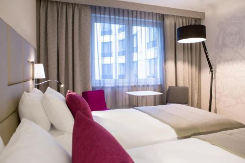 a hotel room with two beds and a window at Mercure Krakow Stare Miasto in Kraków