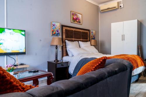 a bedroom with a bed and a couch and a tv at Little Haven! in Rustenburg