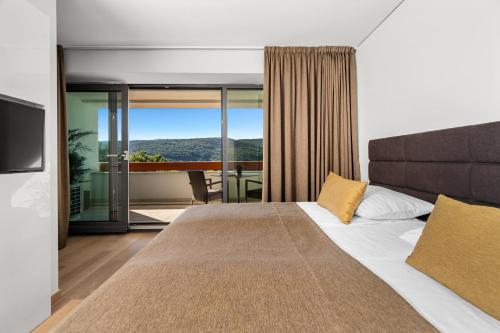 a bedroom with a large bed and a balcony at Park Hill Residences in Rabac