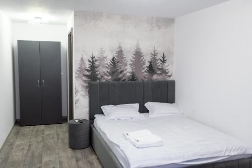 a bedroom with a bed with a painting of trees at Panoramic View Bran Rooms in Bran