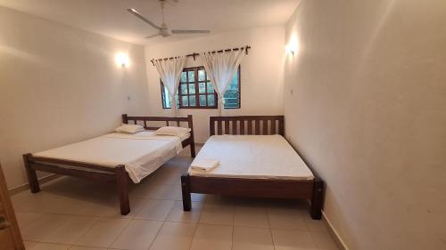 two beds in a room with a window at Malindi Sunset Apartments in Malindi