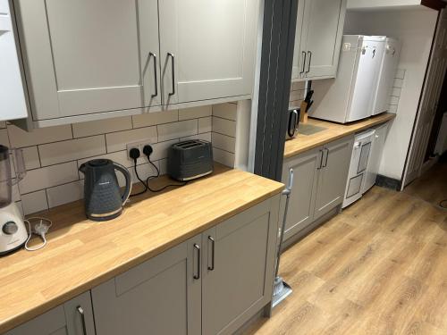 a kitchen with white cabinets and wooden counter tops at Barratt Street En-Suite Rooms in Bristol