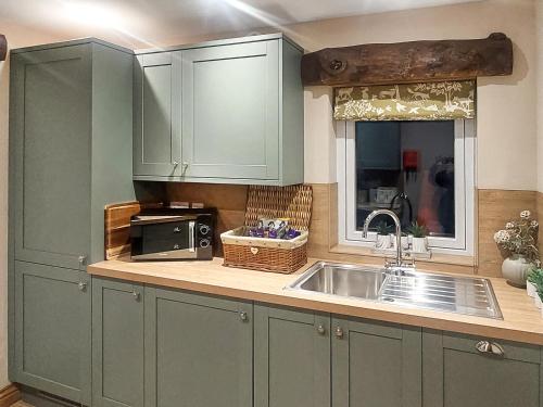a kitchen with green cabinets and a sink at 13 Doomgate Cottage - Uk45056 in Appleby