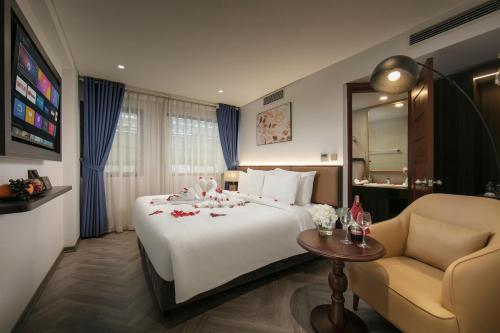 a hotel room with a large white bed and a chair at Sora Hotel Hanoi in Hanoi
