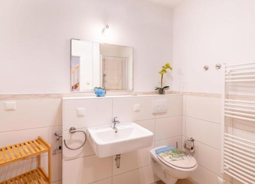 a white bathroom with a sink and a toilet at Haus Hanse in Korswandt