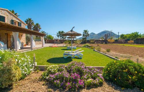 a garden with a umbrella and chairs and flowers at Can Ferrer in Alcudia