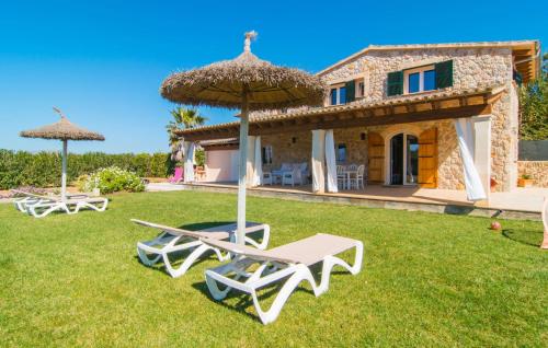 a house with two lawn chairs and an umbrella at Can Ferrer in Alcudia