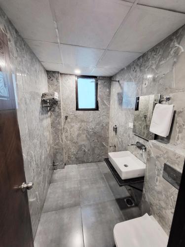 a bathroom with a sink and a toilet and a window at Crestview Inn in Lucknow