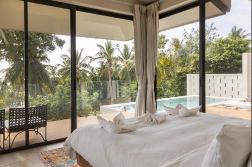 a bedroom with a large white bed and a large window at Ocean Villa in Ko Phangan