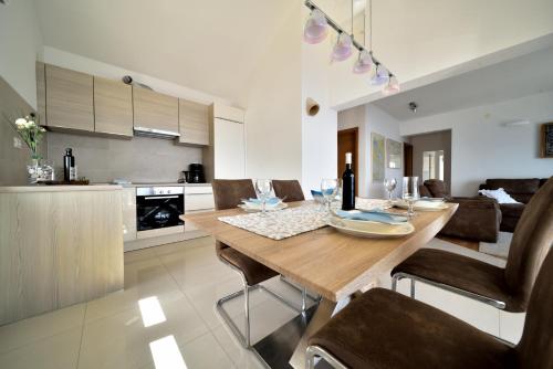 a kitchen and living room with a wooden table and chairs at Seafront Holiday Home - Private Jacuzzi in Blato