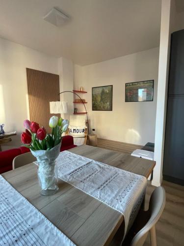 a dining room table with a vase of flowers on it at Appartamento con vista su Brunate in Olgiate Comasco