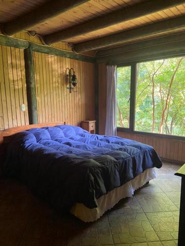 a large blue bed in a room with a window at Cabañas Rahue in Vilches