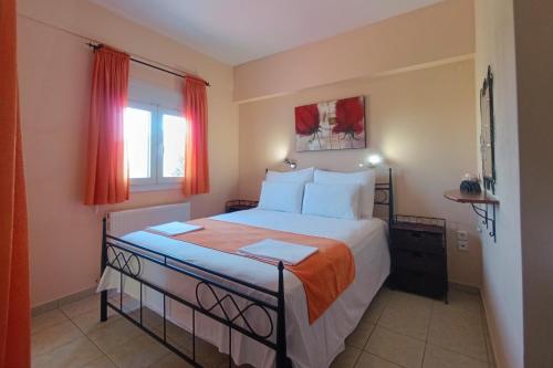 a bedroom with a large bed with red curtains at Nestor Apartments in Chrysi Ammoudia