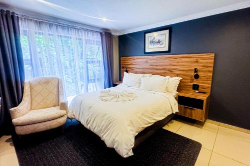 a bedroom with a bed and a chair and a window at The Hide on Aston-Sandton in Johannesburg