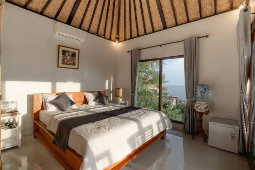 a bedroom with a bed and a large window at Gistari Inn & Restaurant in Seraya