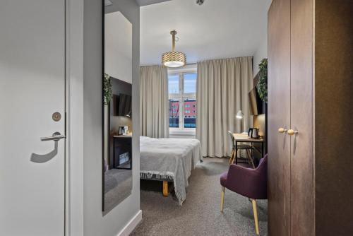 a hotel room with a bed and a table and a window at Home Hotel Astoria in Hamar