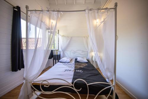 a bedroom with a canopy bed with white curtains at Zenitude Villa - Indoor Pool & Jacuzzi in Jezainville