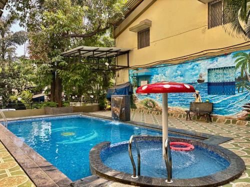 a swimming pool with a red umbrella next to a building at Rajdhani Resort Lonavala in Lonavala
