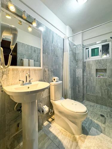 a bathroom with a sink and a toilet and a mirror at Casa Delfin in Playa del Carmen