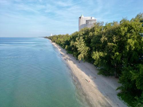 a beach with trees and a building in the background at Coastal Nomad Ocean View Stay - 1 or 2 Rooms in Ban Pak Khlong Phe