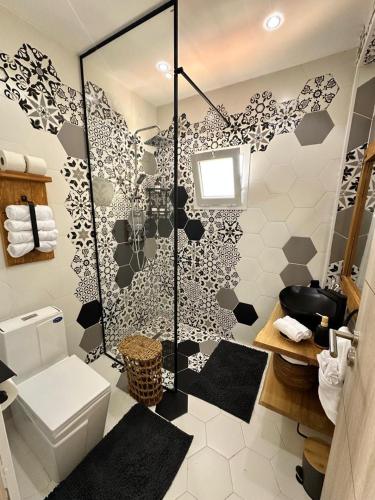 a bathroom with a shower with black and white tiles at Telemly Douira el ALIA Alger in LʼAgha