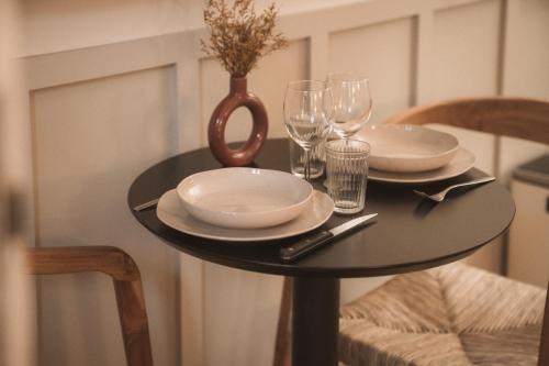 a black table with plates and glasses and a vase at Sezam Appart-Hotel Rennes in Rennes