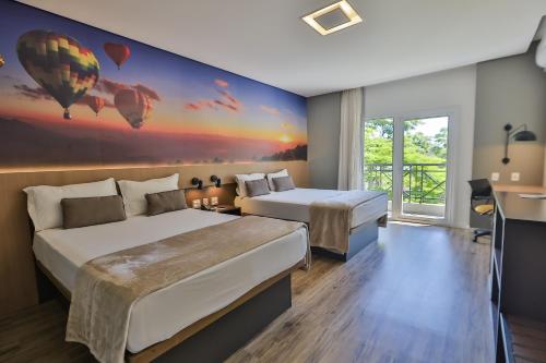 a hotel room with two beds and a painting of hot air balloons at Hotel Panamby Guarulhos in Guarulhos