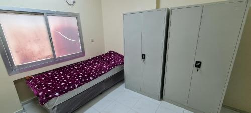 a small room with a bed with a purple blanket at Men-only house in Khor Fakkan in Khor Fakkan