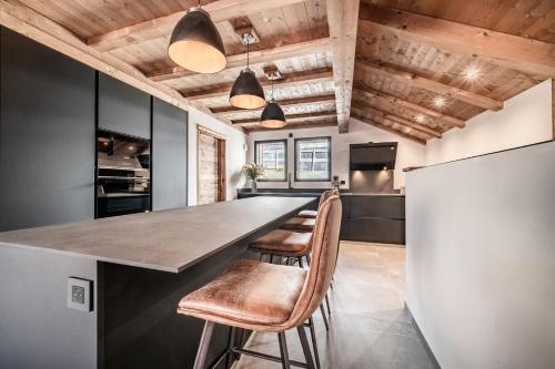 a kitchen with a bar with stools and a refrigerator at Apartment Danton, Châtel - by EMERALD STAY in Châtel