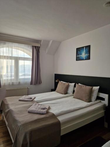 a bedroom with a large bed with two towels on it at Erdős Panzió in Ditrău