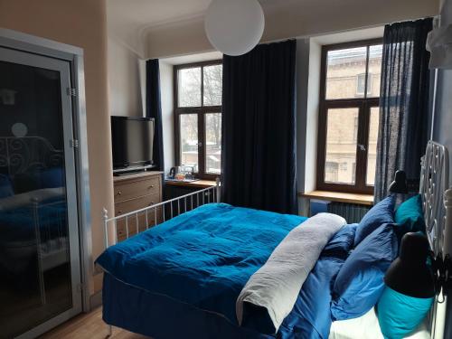 a bedroom with a blue bed and a television at Red Doors Apartament 23 Free Parking in Riga