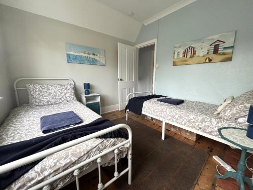 a bedroom with two beds and a table in it at Downs Gate Cottage in Eastbourne