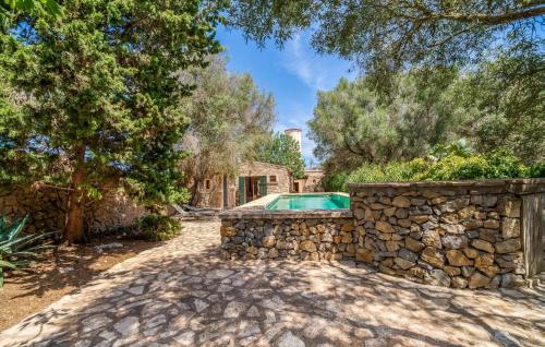 a home with a stone wall and a swimming pool at Moli Den Guixo in Artá