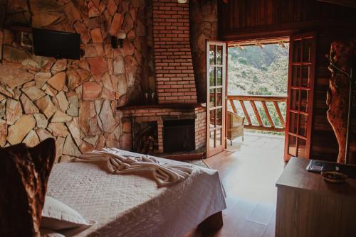 a bedroom with a stone wall with a bed and a fireplace at Pousada Peterle in Domingos Martins