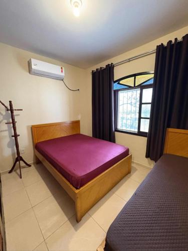 a bedroom with a bed and a window with a fan at Casa com piscina in Bertioga