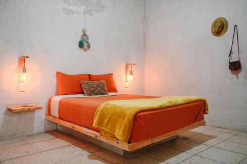 a bedroom with a bed with an orange blanket on it at Co404 Oaxaca - Coliving Coworking in Oaxaca City