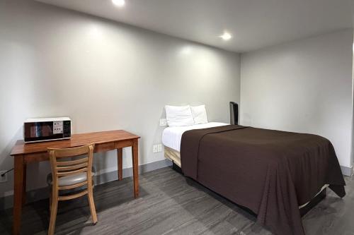 a small bedroom with a bed and a desk with a microwave at 6 Rivers Motel Fortuna near Hwy 101 in Fortuna