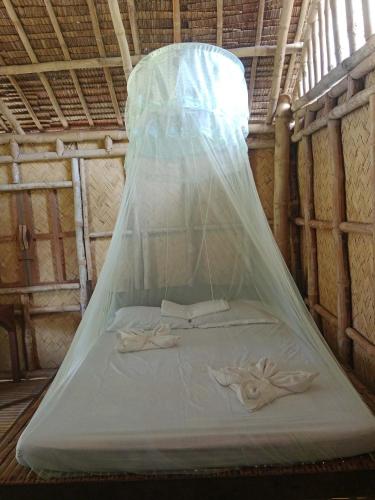 a bed in a room with a mosquito net at Bamboo Basecamp in El Nido