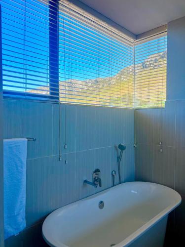 a white tub in a bathroom with a window at House Vos in Hermanus