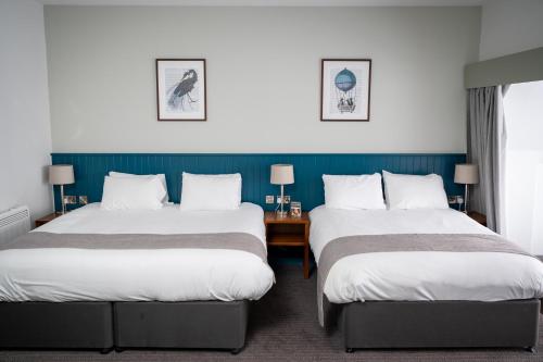 Una habitación de hotel con dos camas y un escritorio. en The Caledonian Hotel, en Leven