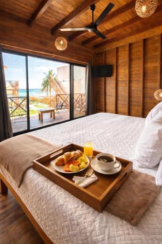 a tray of food on a bed with a view of the ocean at Hotel Solana Bacalar Lakefront in Bacalar