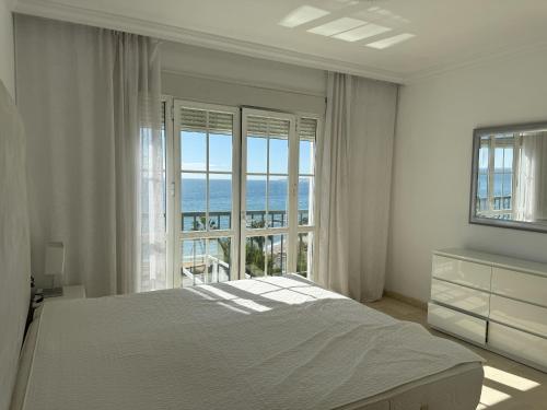 a white bedroom with a bed and a large window at Mediterranean Escape with Panoramic Sea Views in Benalmádena