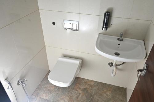 a white bathroom with a toilet and a sink at The Shrine Hotel in Godarpura